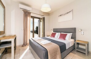 Un dormitorio con cama, escritorio, aire acondicionado, ventana con cortinas y vista al exterior.