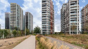 Un ensemble immobilier résidentiel moderne comprenant plusieurs immeubles à étages, un chemin piétonnier et une route.