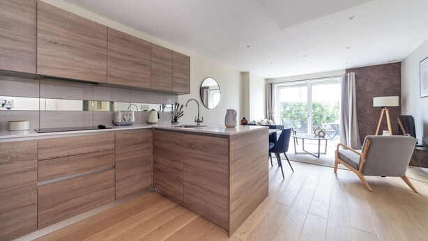 Une cuisine moderne avec des meubles en bois, un îlot central et un coin repas comprenant une chaise et une table.