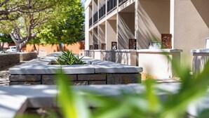 A building with a stone pathway, a tree, and a series of framed artworks on the wall. - Defiance House Lodge (Bullfrog)