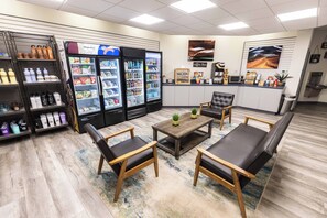 A coffee shop interior with seating, a coffee bar, and beverage dispensers.