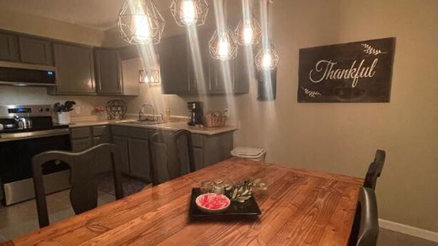 Een eetruimte met een houten tafel, stoelen en een bord waarop 'Thankful' staat.