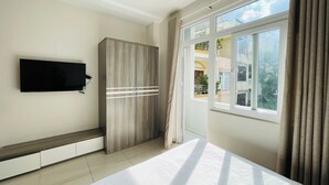 A bedroom with a bed, a wardrobe, a television, and a window with curtains. - Stay Central-Prestige Address &Private Comfort. (Thành phố Hồ Chí Minh)
