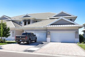 Une maison d’habitation avec un garage, une allée et un camion garé.