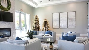 Ein modernes Wohnzimmer mit grauen Sofas, einem Kamin, zwei Weihnachtsbäumen und abstrakter Wandkunst.
