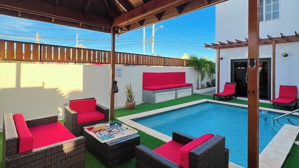 An outdoor patio with wicker furniture and a pool. - Spacious 6-bedroom villa at Hellshire w/ private pool, games room & gym (Portmore)