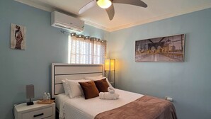 A bedroom with a bed, nightstand, and a ceiling fan. - Spacious 6-bedroom villa at Hellshire w/ private pool, games room & gym (Portmore)