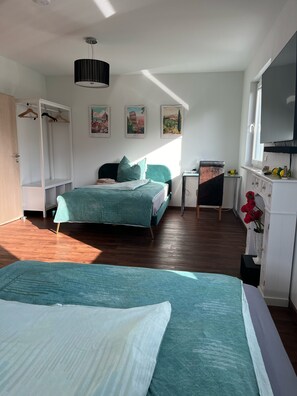 Un dormitorio con cama, escritorio, armario y televisión.