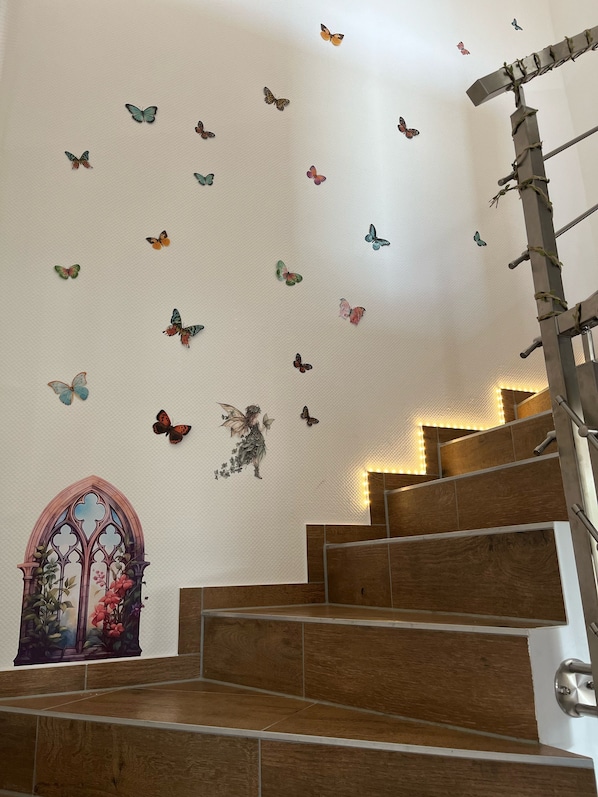A staircase with wooden steps and a wall decorated with butterfly decals. - Ferienwohnungen im Grund 22 (Hoppegarten)