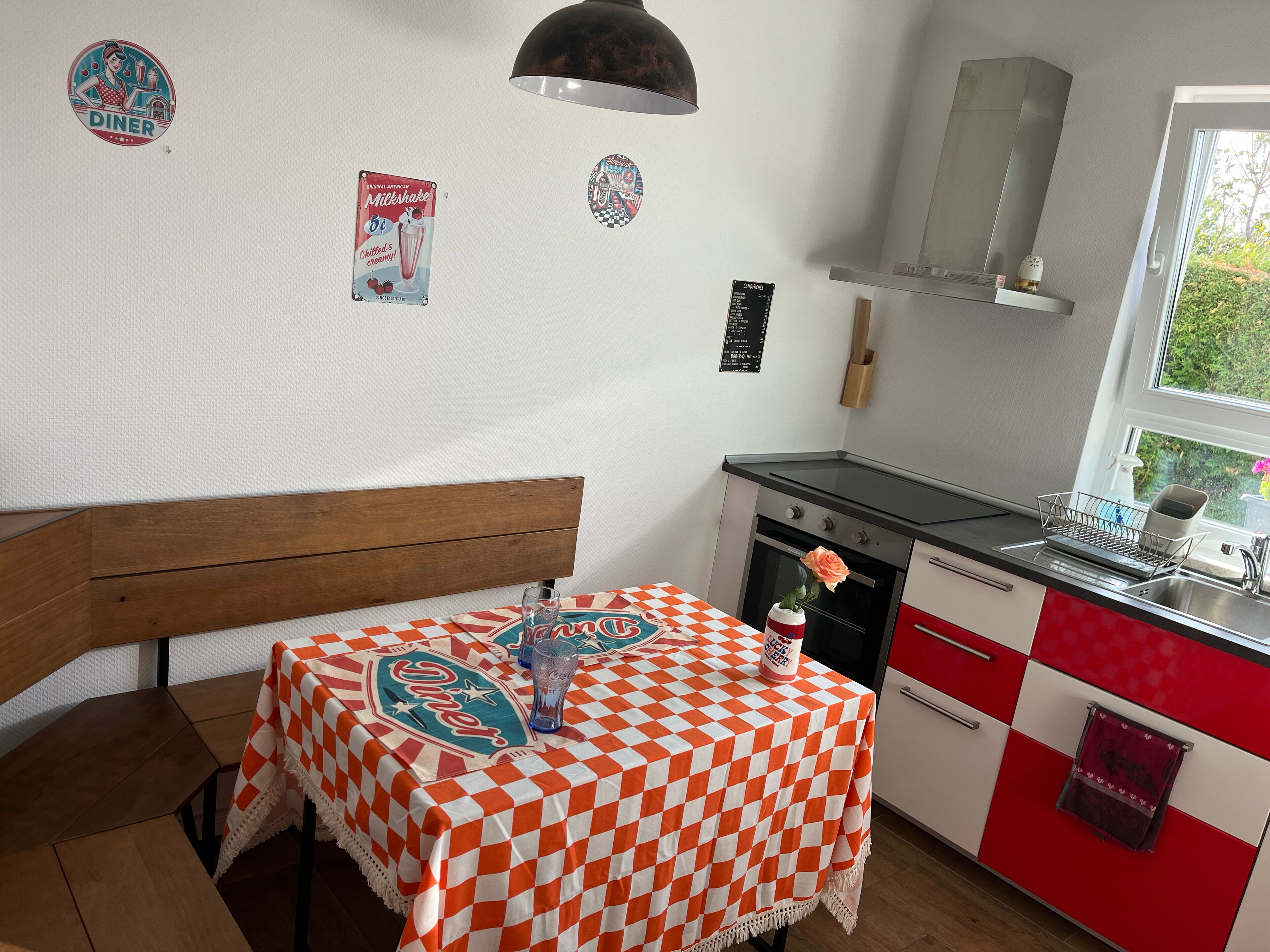 Una cucina con una tovaglia a quadri, una panca di legno, un fornello e un lavello.