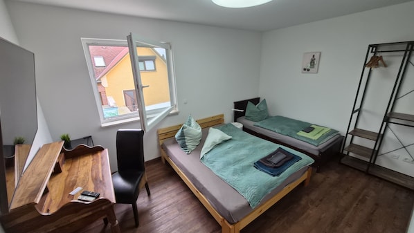 A small, tidy room with a desk, two beds, a chair, a window, and a ladder. - Ferienwohnungen im Grund 22 (Hoppegarten)