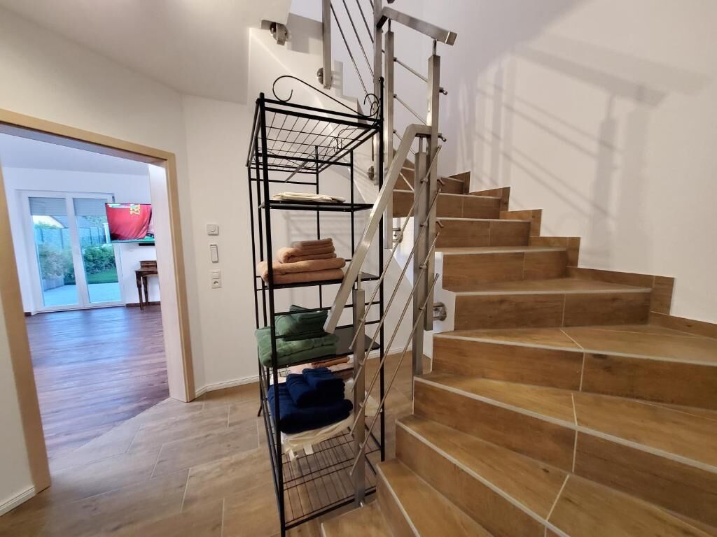 A staircase with a metal railing and a built-in storage unit with folded blankets.