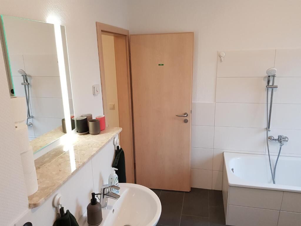 Un baño con lavamanos, espejo y ducha.