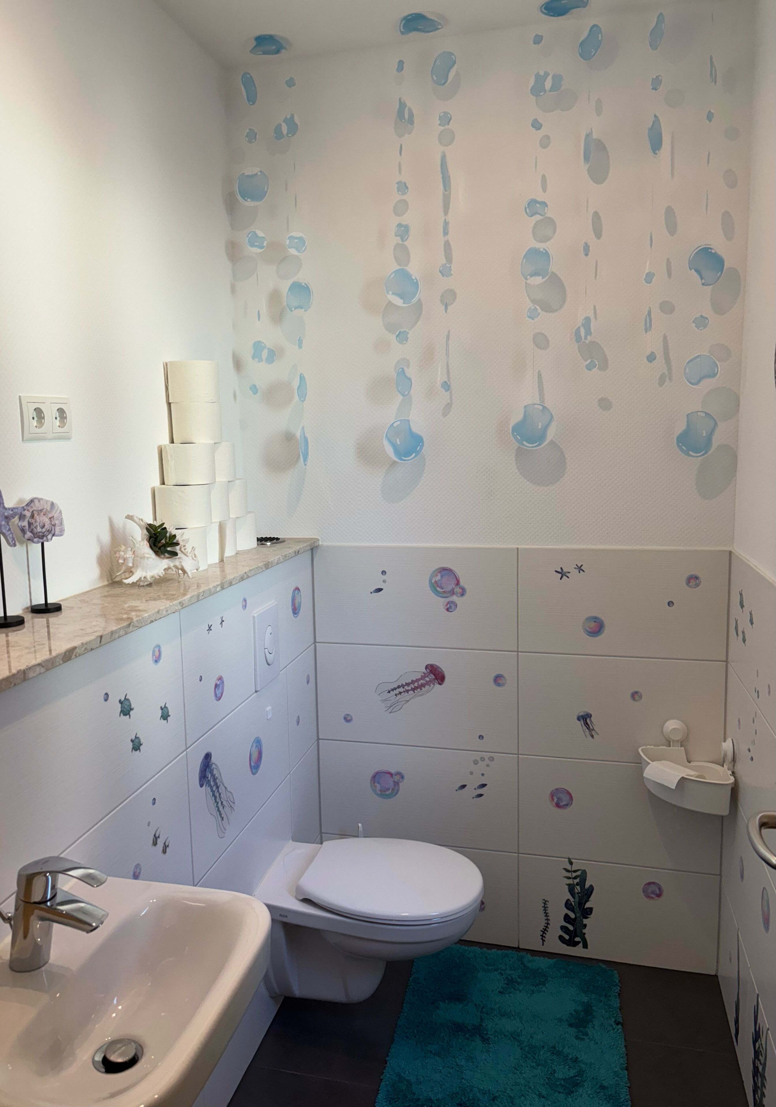 Une salle de bain équipée de toilettes, d’un lavabo et de carreaux muraux décoratifs.