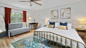 Ein Schlafzimmer mit einem Bett, einem Schreibtisch, einem Sessel, einer Couch und einem Deckenventilator.