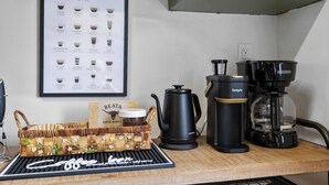 Eine Küchenarbeitsplatte mit einer Kaffeemaschine, einer gerahmten Kaffeespezialitätenkarte und einem Kaffeebohnenglas.