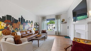 Ein Wohnzimmer mit Sofa, Sessel und einem an der Wand befestigten Fernseher.