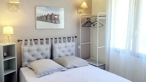 A neatly arranged bedroom with a bed, bedside lamps, a coat rack, and a framed picture on the wall. - 4-bedroom villa, nature, quiet, panoramic mountain views (Salles-et-Pratviel (31110))