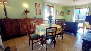 A dining area with a table set for four, surrounded by wooden chairs. A vase with flowers is on the table, and there are framed pictures on the wall. - 4-bedroom villa, nature, quiet, panoramic mountain views (Salles-et-Pratviel (31110))