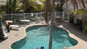 A swimming pool with a curved edge, surrounded by a white fence, and a sign indicating a maximum depth of 6 feet.