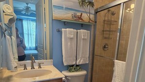 A bathroom with a vanity, sink, mirror, and a shower area.