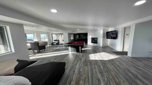 Un salon moderne avec une table de billard, un canapé et une cheminée.