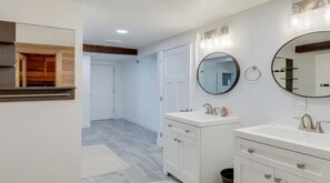Ein modernes Badezimmer mit zwei Waschbecken, einem großen Spiegel und einem Holzschrank.
