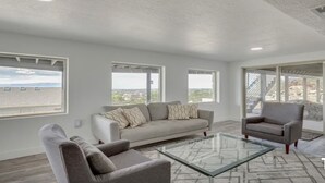 Ein modernes Wohnzimmer mit einer Couch, einem Sessel und einem Glastisch.