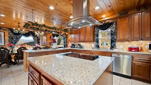 A spacious kitchen with wooden cabinets, granite countertops, and a central island. - 360° Mountaintop Views | Hogwarts Room, 19-Seat Theater & 2 Pubs (Sevierville)