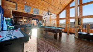 A wooden interior with pool tables, a bar area, and large windows offering a view. - 360° Mountaintop Views | Hogwarts Room, 19-Seat Theater & 2 Pubs (Sevierville)