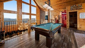 A wooden interior with a pool table, large windows, and a telephone booth. - 360° Mountaintop Views | Hogwarts Room, 19-Seat Theater & 2 Pubs (Sevierville)