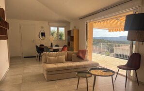 A living room with a sofa, a dining table, and chairs. There is a balcony with a view of the countryside. - House with swimming pool and 5 bedrooms (Porto-Vecchio)