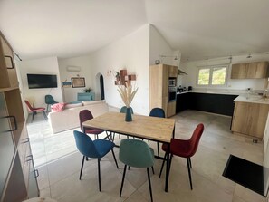 A modern kitchen with a dining area, featuring a wooden table and chairs, a flat-screen TV, and a large window. - House with swimming pool and 5 bedrooms (Porto-Vecchio)