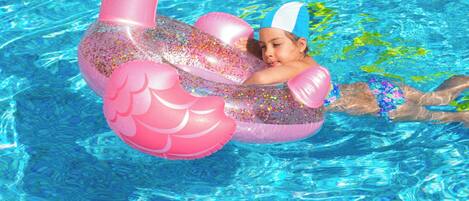 A person in a pool with a pink flamingo float.