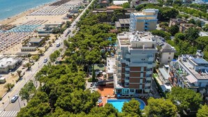 A coastal cityscape with a beach, a row of beachside villas, and a central building with a pool. - Hotel Atlantic (Giulianova)