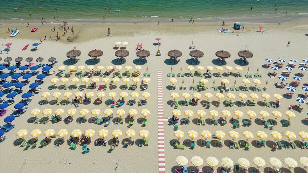 A beach with rows of sun loungers and umbrellas, a lifeguard tower, and a clear view of the ocean. - Hotel Atlantic (Giulianova)