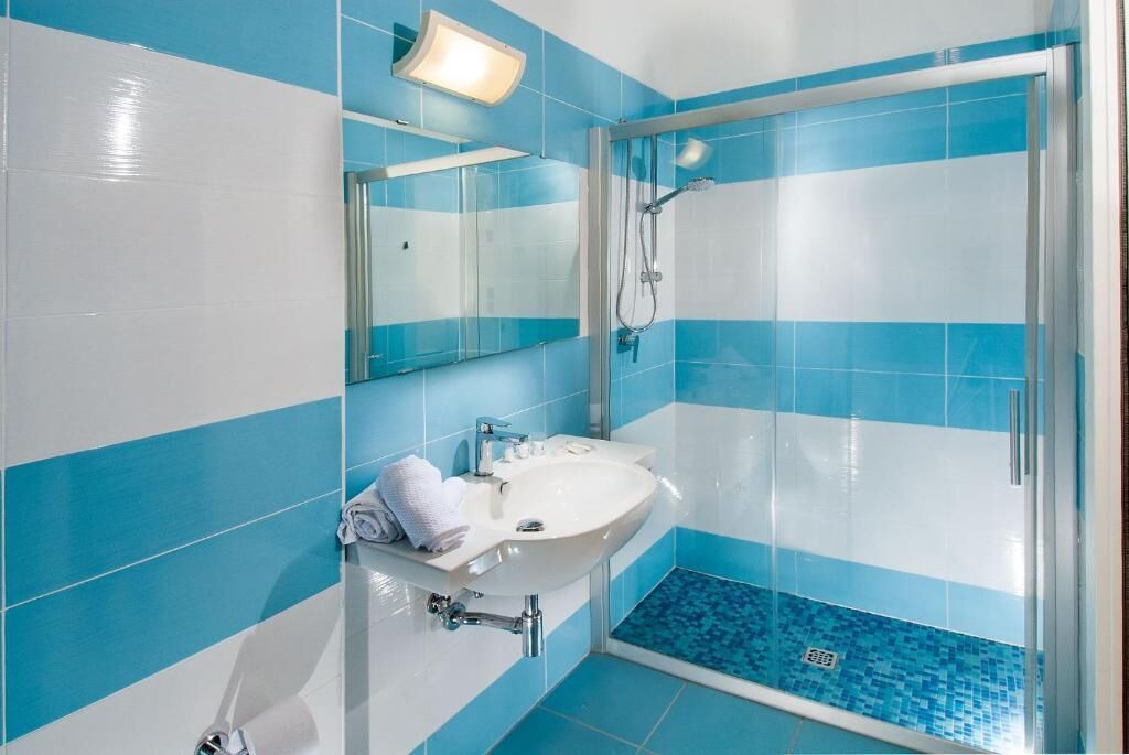 Ein Badezimmer mit Glasdusche, einem weißen Waschbecken und einem Spiegel.