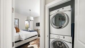 Une chambre à coucher avec un lit, un tapis à motifs zébrés, une lampe suspendue et un téléviseur fixé au mur.