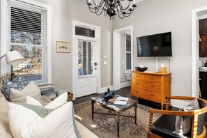 A living room with a sofa, a coffee table, a wooden dresser, and a television. - Step into the coziest two bedroom! (Columbus)