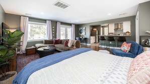 A spacious living area with a large bed, a sofa, and a dining area with a kitchen in the background. - Blue Lotus, LUXE Cottage, in walkable Kennett Square near Longwood Gardens (Kennett Square)
