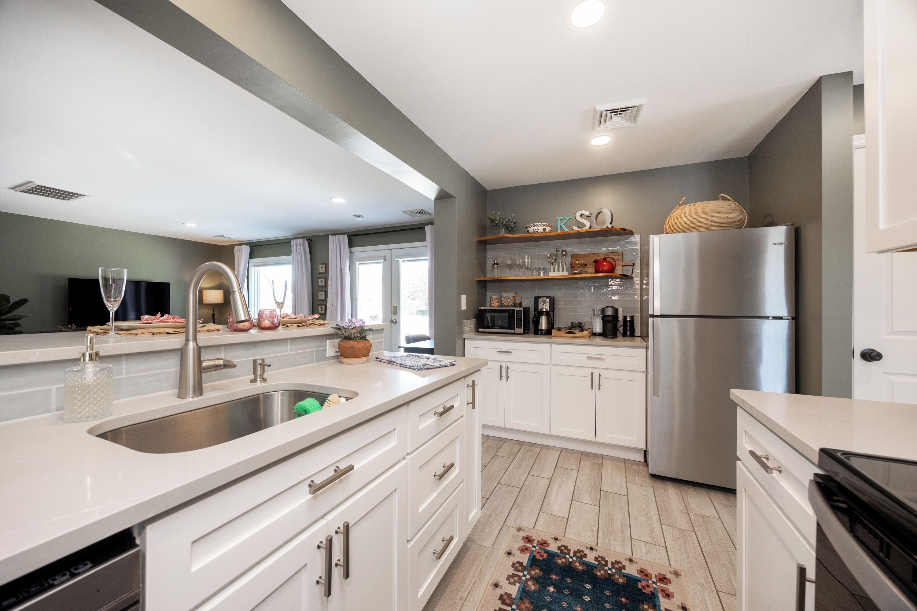A modern kitchen with white cabinetry, stainless steel appliances, and a central island with a sink.