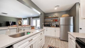 A modern kitchen with white cabinetry, stainless steel appliances, and a central island with a sink.