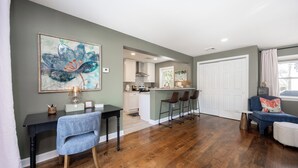 A spacious living area with a dining table, a blue sofa, and a kitchen in the background. - Blue Lotus, LUXE Cottage, in walkable Kennett Square near Longwood Gardens (Kennett Square)
