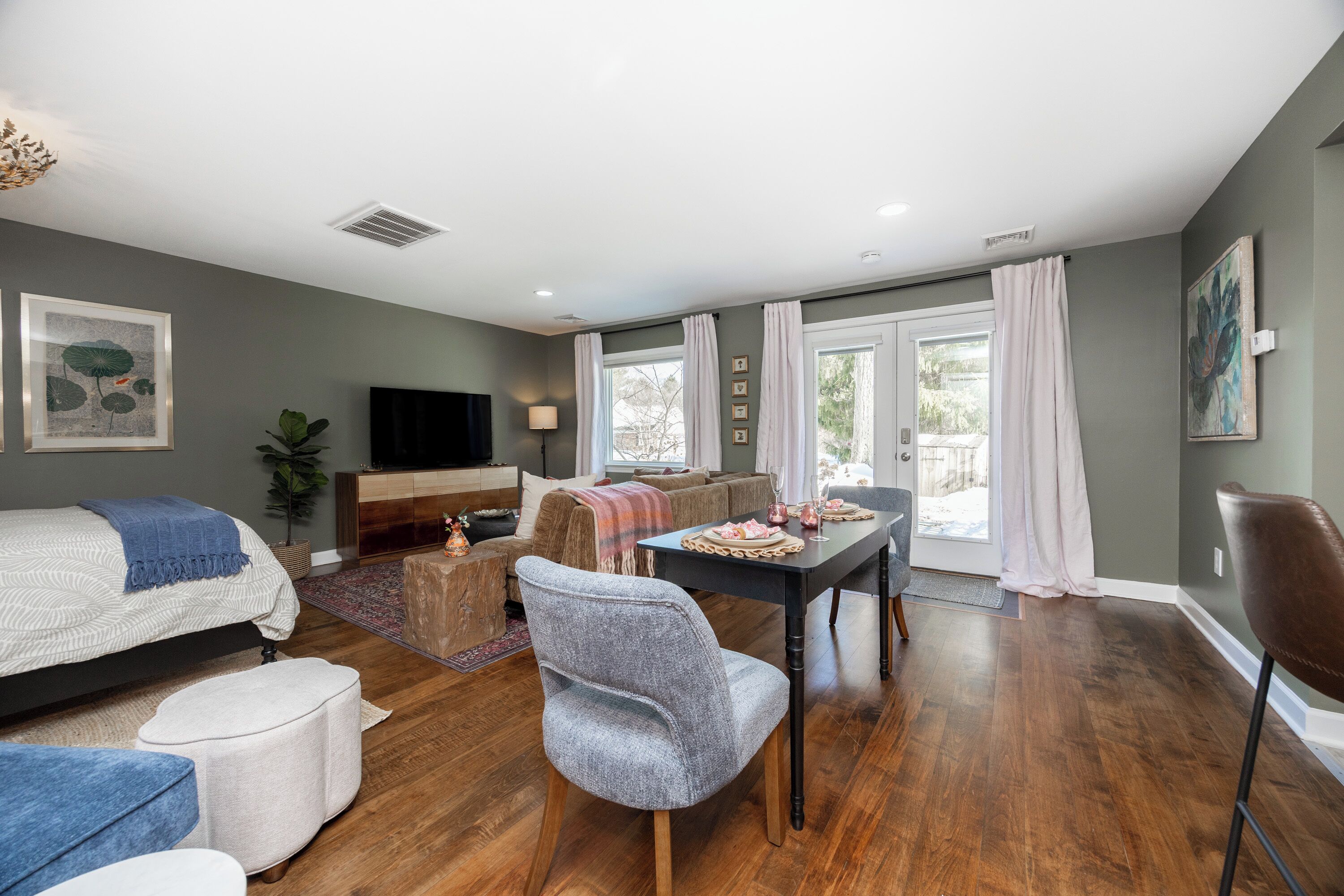 A spacious living room with a sofa, ottoman, and dining table.