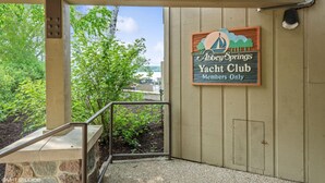 A sign for Abbey Springs Yacht Club with a view of a dock and greenery.