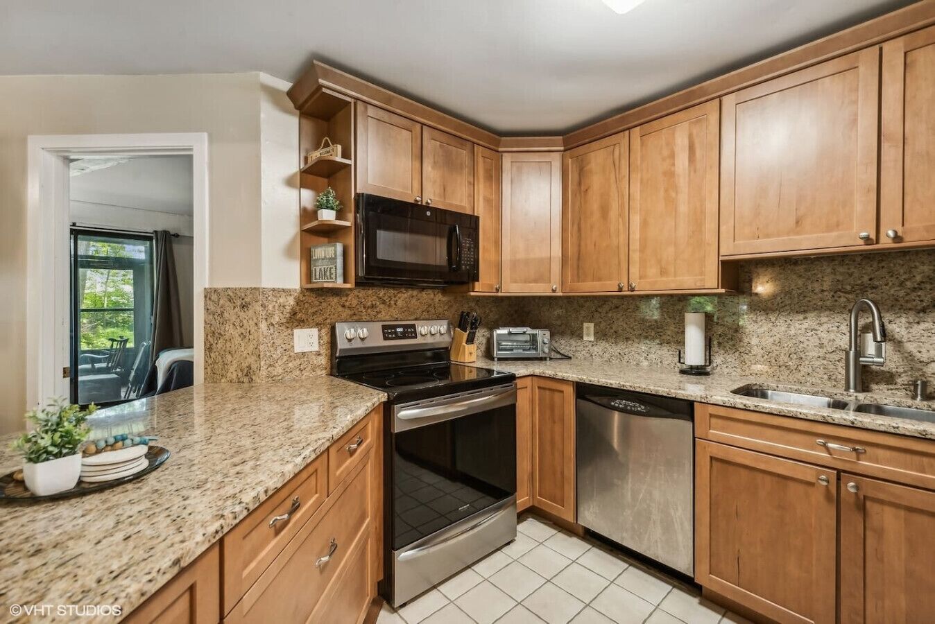 A kitchen with wooden cabinets, granite countertops, a microwave, stove, oven, dishwasher, and a sink.