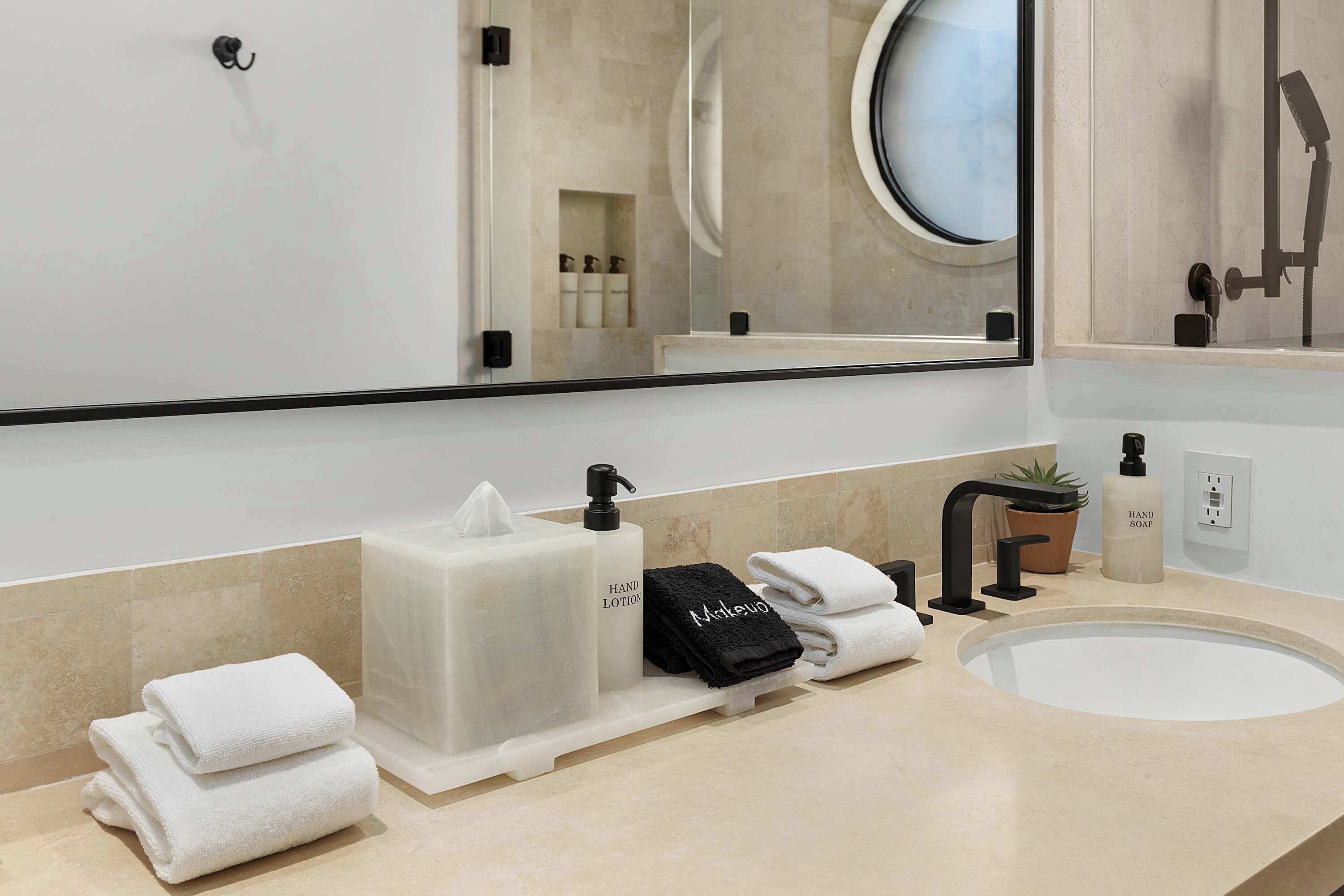 Une salle de bain moderne avec un grand miroir, un lavabo et des serviettes soigneusement pliées.