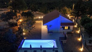 A modern building with a swimming pool, outdoor seating, and a well-lit patio area. - Villa  Ika (Raščane)