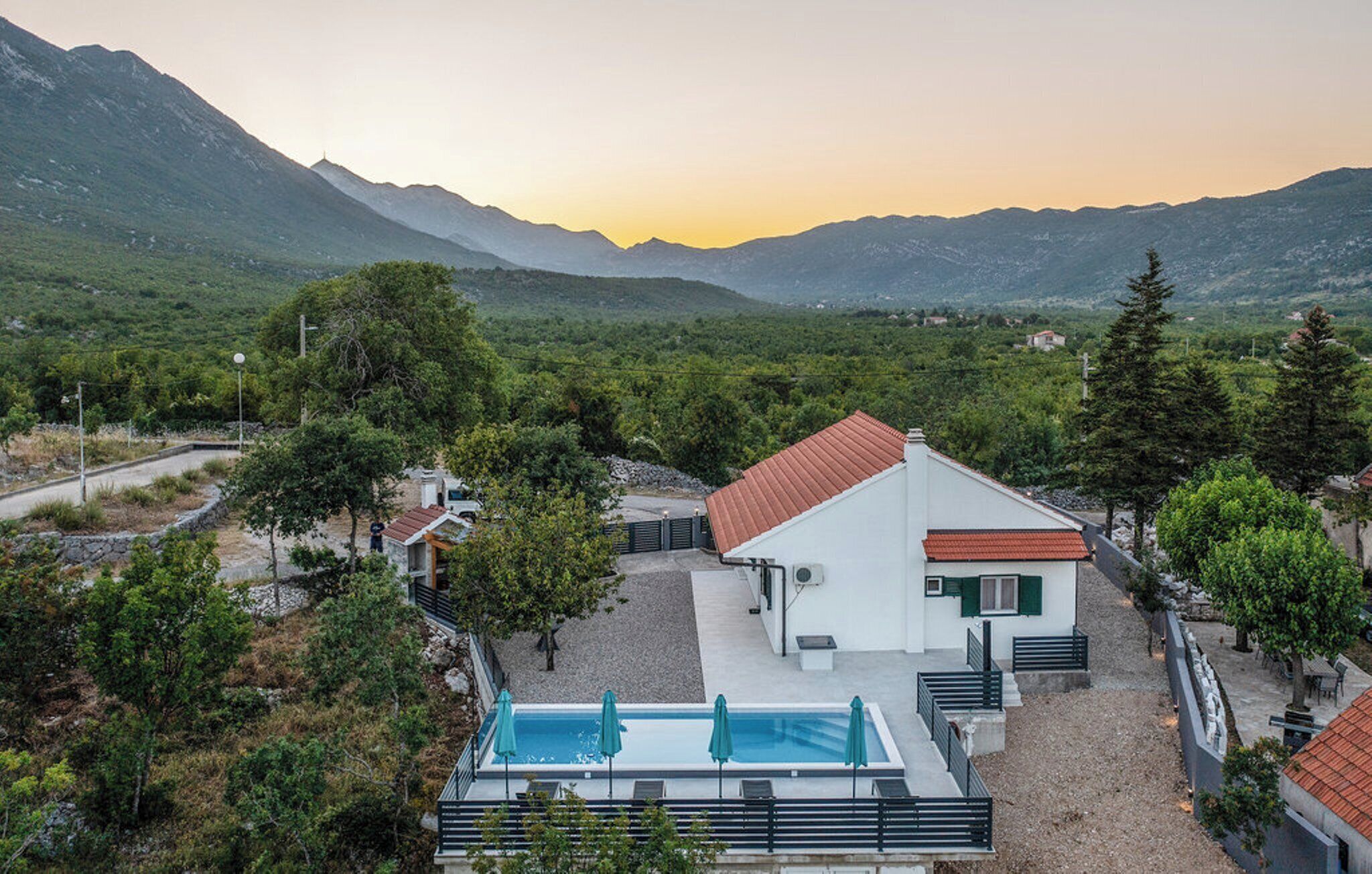 Eine moderne Villa mit Schwimmbad, umgeben von üppiger Vegetation und Bergen.