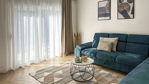 A living room with a blue sofa, a coffee table, and a patterned rug. - Villa  Ika (Raščane)